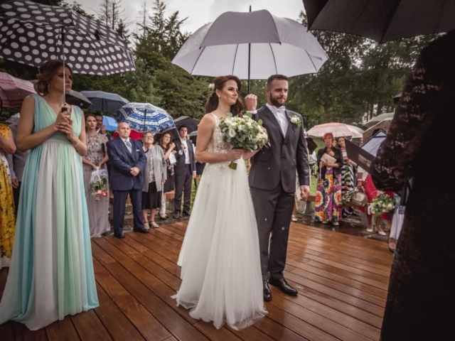 Svatební obřad na louce v děšti - ženich drží deštník